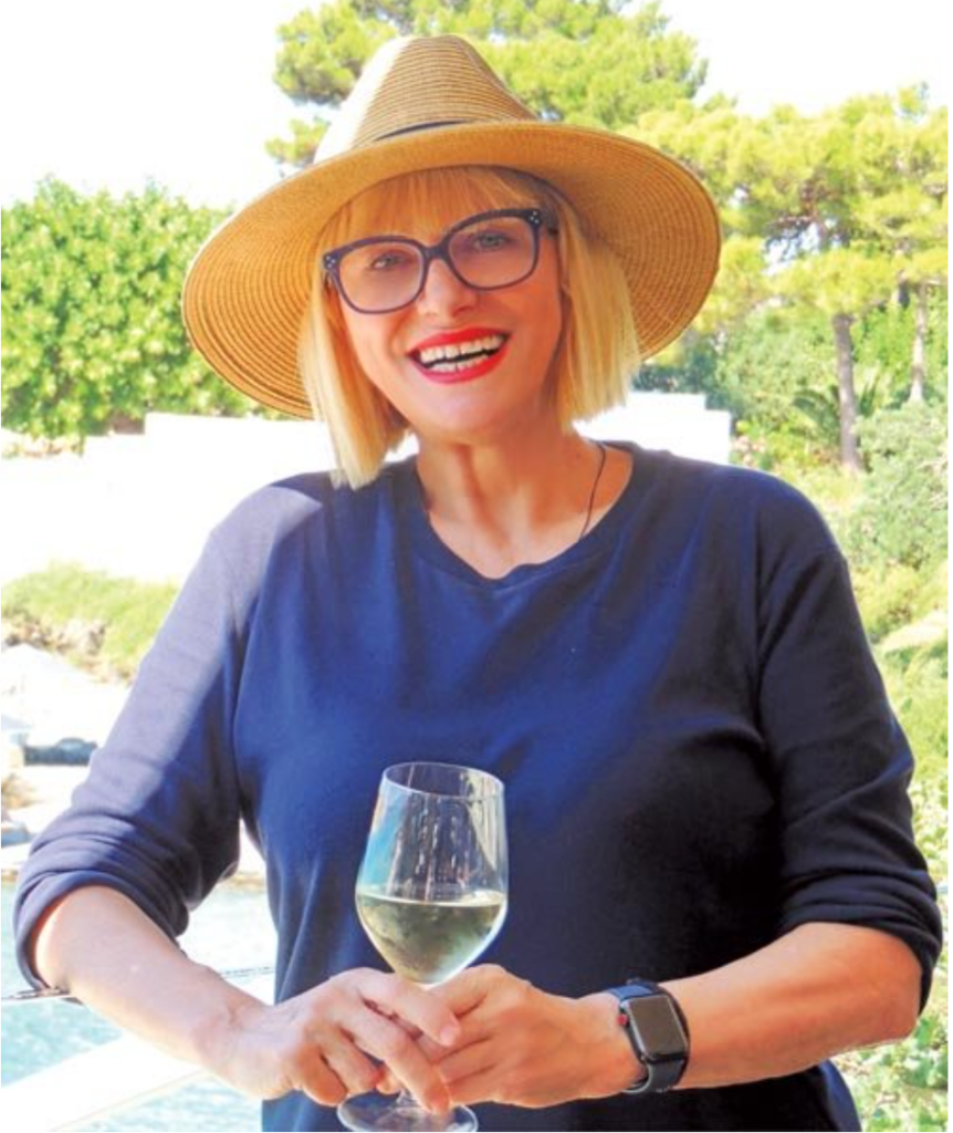 a person wearing a hat and holding a glass of wine